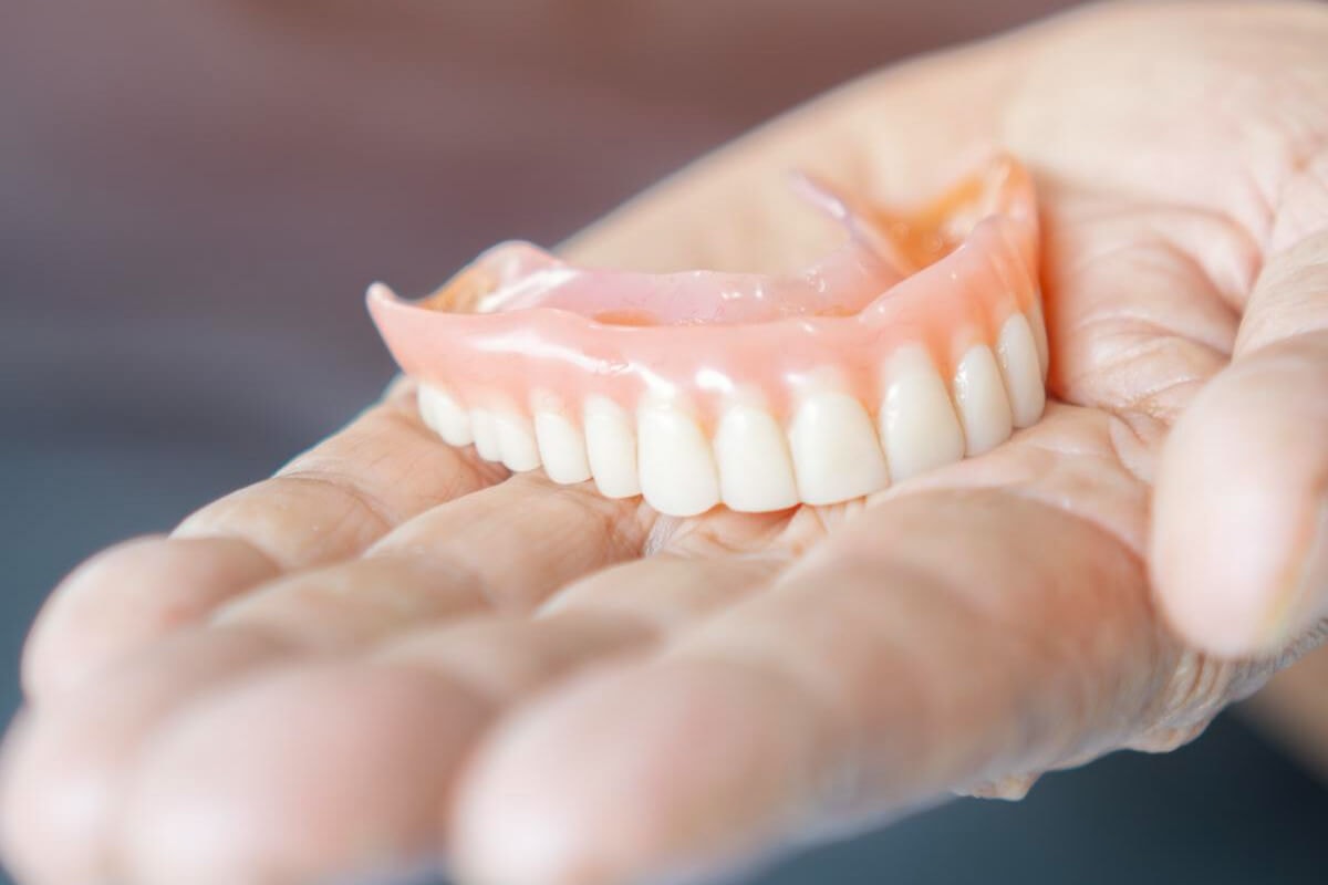Hand holding a full upper denture