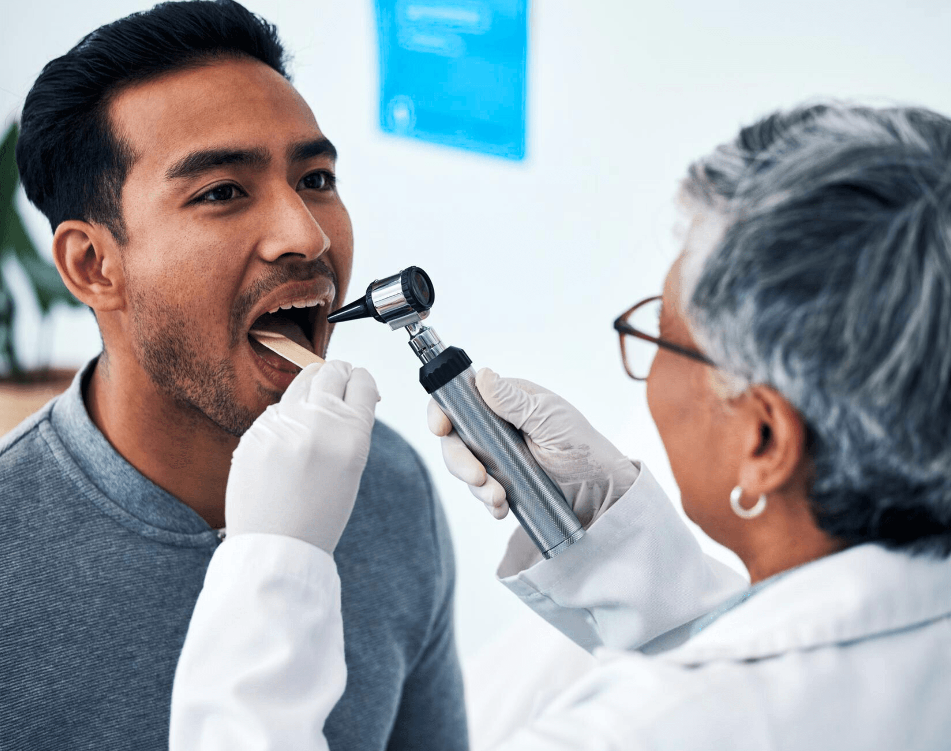 Clinician examining a man's mouth with a light